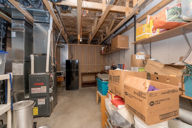 basement with heating unit and black fridge