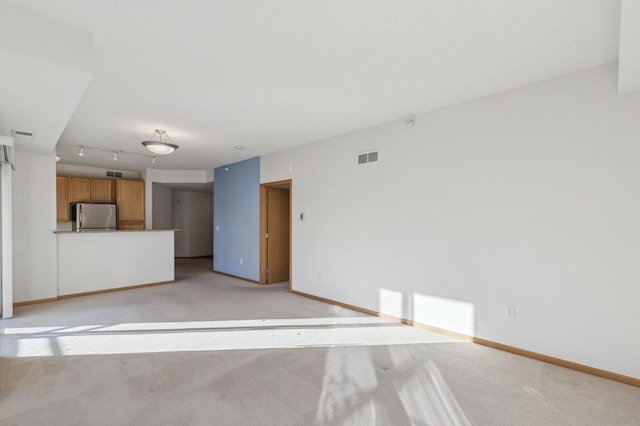 unfurnished living room featuring track lighting and light colored carpet