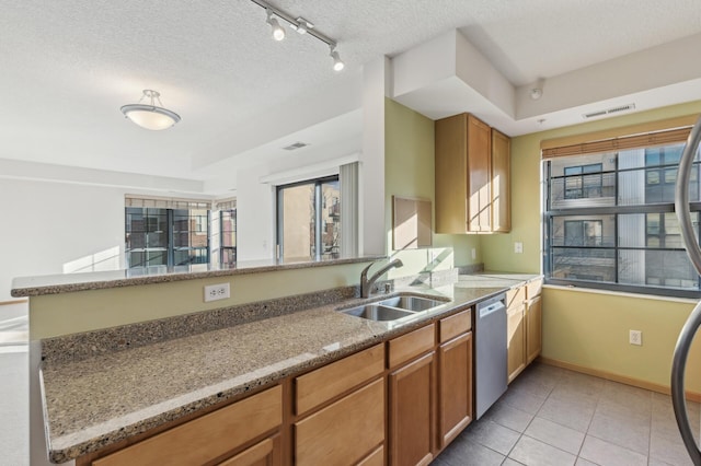 kitchen with light stone countertops, kitchen peninsula, sink, and dishwasher