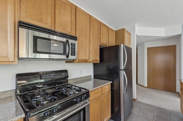 kitchen featuring stainless steel appliances, light stone countertops, a textured ceiling, and light tile patterned floors