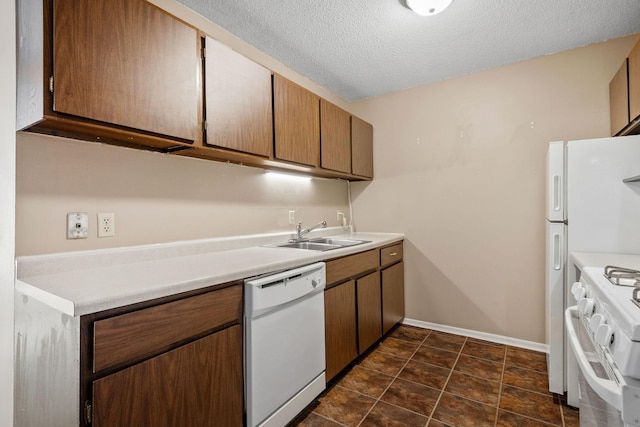 kitchen with white appliances, sink, and a textured ceiling