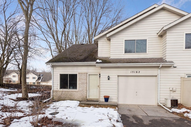 view of front of property featuring brick siding, driveway, a shingled roof, and a garage