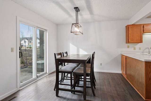 dining space featuring visible vents, dark wood-style floors, baseboards, and a textured ceiling