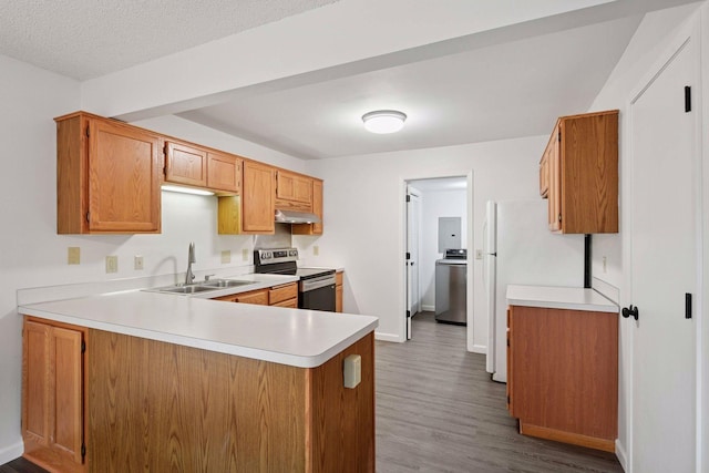 kitchen featuring stainless steel electric range oven, light countertops, a peninsula, freestanding refrigerator, and a sink