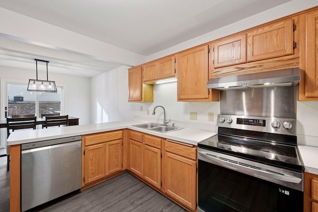 kitchen featuring light countertops, a peninsula, stainless steel appliances, wall chimney exhaust hood, and a sink