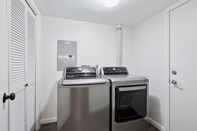 clothes washing area with wood finished floors, baseboards, laundry area, electric panel, and washer and clothes dryer