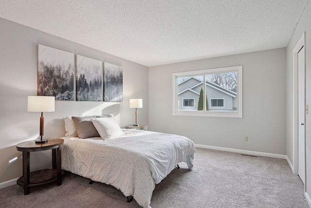 bedroom with visible vents, a textured ceiling, baseboards, and carpet floors