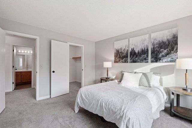 bedroom with a spacious closet, light colored carpet, and baseboards