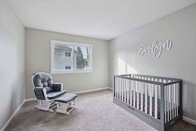 bedroom featuring a crib, a textured ceiling, baseboards, and carpet floors