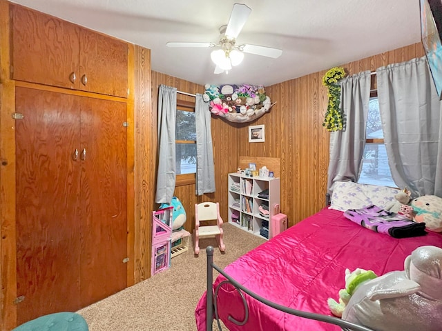 carpeted bedroom featuring ceiling fan and wooden walls