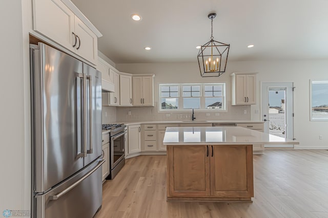 kitchen with pendant lighting, sink, white cabinetry, stainless steel appliances, and a kitchen island