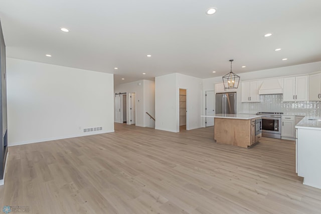 kitchen featuring decorative light fixtures, white cabinetry, custom exhaust hood, a center island, and stainless steel appliances