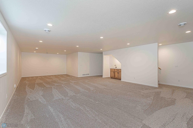 interior space featuring sink, light colored carpet, and a textured ceiling