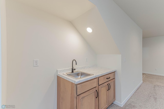 kitchen with vaulted ceiling, light colored carpet, and sink