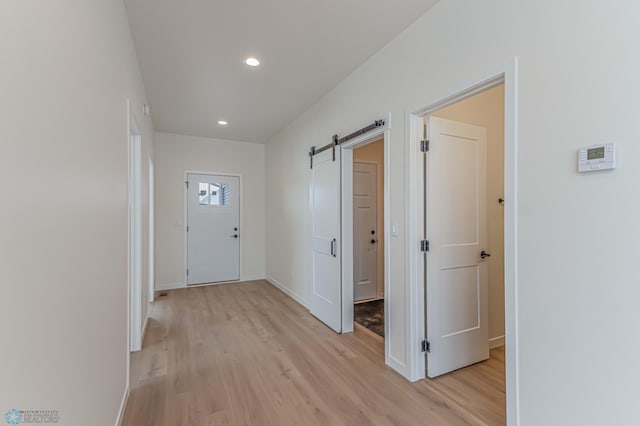 corridor featuring a barn door and light hardwood / wood-style floors