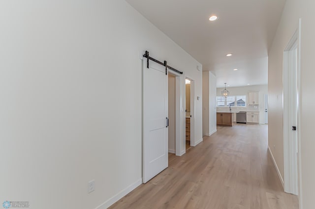 hallway with a barn door and light hardwood / wood-style flooring