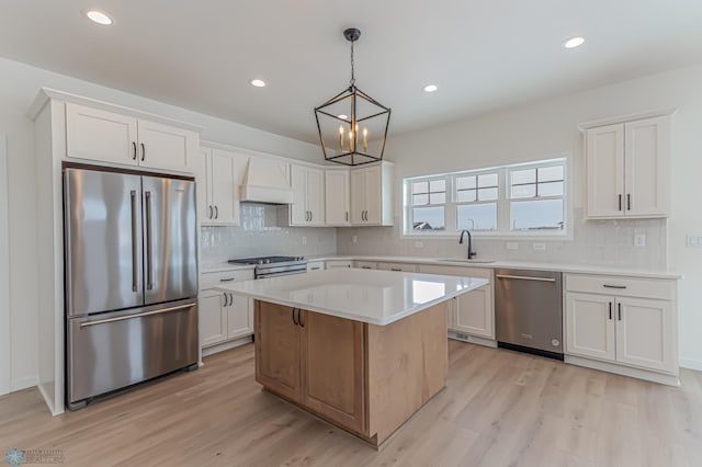 kitchen featuring white cabinets, hanging light fixtures, a center island, stainless steel appliances, and custom range hood