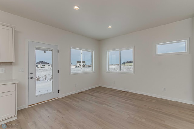 spare room featuring plenty of natural light and light hardwood / wood-style floors
