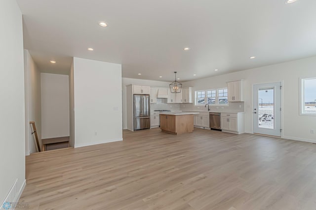 kitchen with white cabinetry, stainless steel appliances, a center island, and hanging light fixtures