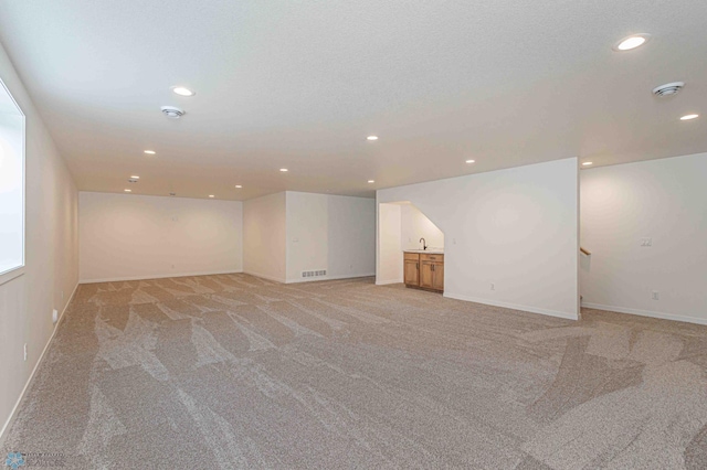 interior space with sink, light colored carpet, and a textured ceiling