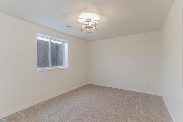 carpeted empty room with an inviting chandelier
