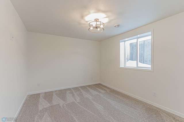 carpeted spare room with an inviting chandelier