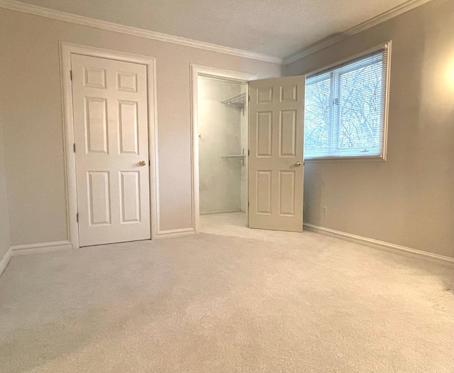 unfurnished bedroom with light carpet, crown molding, and a closet