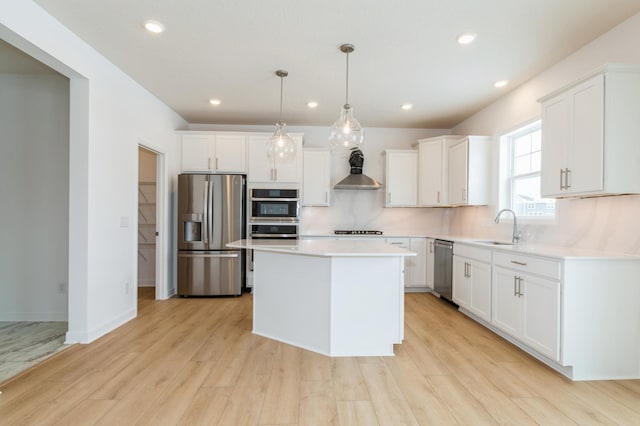 kitchen featuring sink, appliances with stainless steel finishes, white cabinetry, a center island, and decorative light fixtures