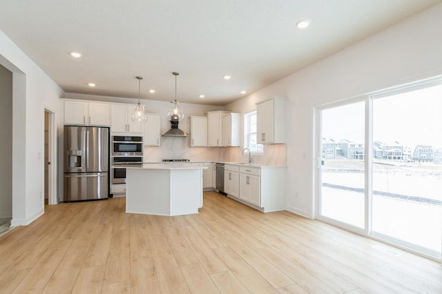 kitchen featuring stainless steel appliances, a center island, hanging light fixtures, and white cabinets