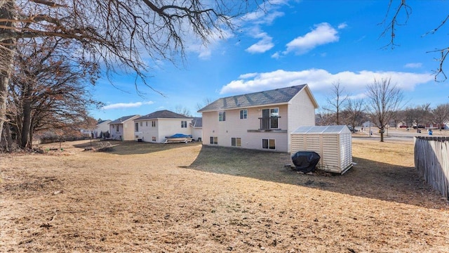 back of house with fence, a lawn, and an outbuilding