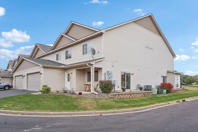 view of front of house with cooling unit, a garage, and a front lawn