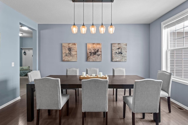 dining room with wood-type flooring and a textured ceiling