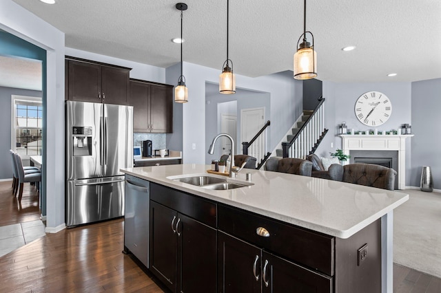 kitchen with sink, hanging light fixtures, an island with sink, and appliances with stainless steel finishes