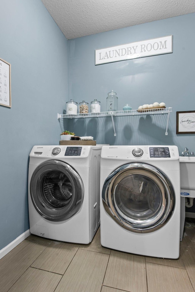 clothes washing area featuring a textured ceiling and washer and clothes dryer