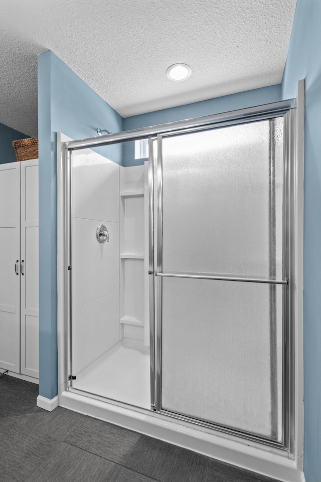 bathroom featuring a shower with shower door and a textured ceiling