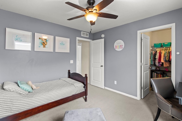 bedroom with light carpet, a spacious closet, a closet, and ceiling fan