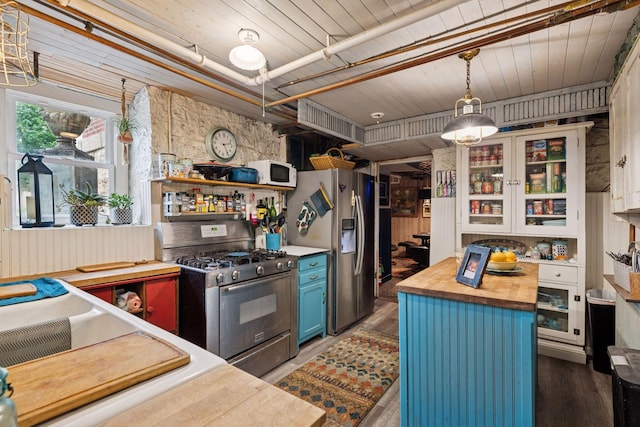 706 4th St, Red Wing, MN 55066 - kitchen featuring appliances with stainless steel finishes, wood counters, blue cabinets, wood finished floors, and hanging light fixtures