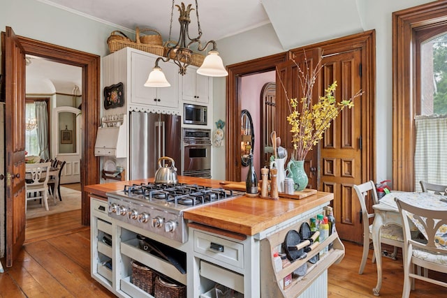 706 4th St, Red Wing, MN 55066 - kitchen with stainless steel appliances, wooden counters, white cabinets, light wood-style flooring, and ornamental molding