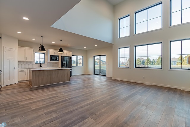 unfurnished living room with hardwood / wood-style flooring, sink, and a high ceiling