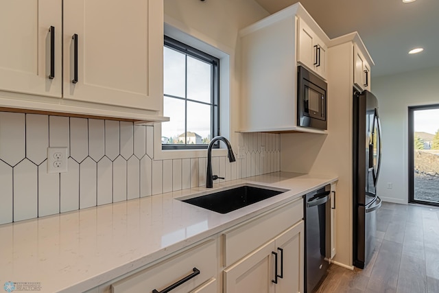 kitchen with sink, black appliances, light stone countertops, white cabinets, and decorative backsplash