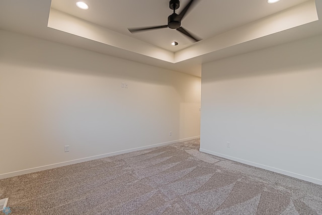 unfurnished room with ceiling fan, a tray ceiling, and carpet flooring