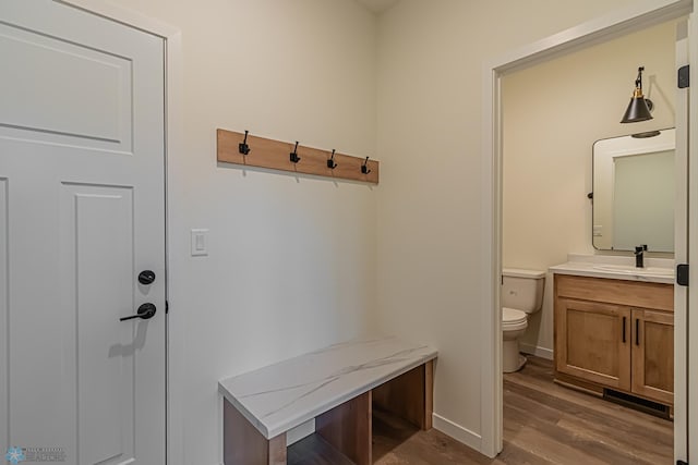 mudroom with baseboards, a sink, and wood finished floors