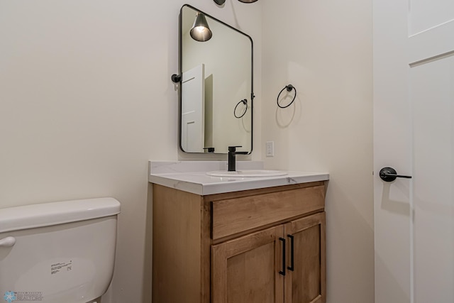 half bath featuring vanity and toilet