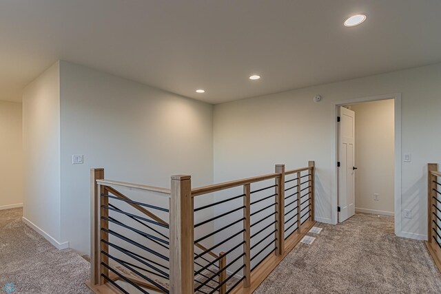 hallway with carpet floors, baseboards, recessed lighting, and an upstairs landing