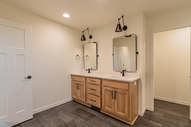 full bath featuring baseboards, a sink, wood finished floors, and double vanity