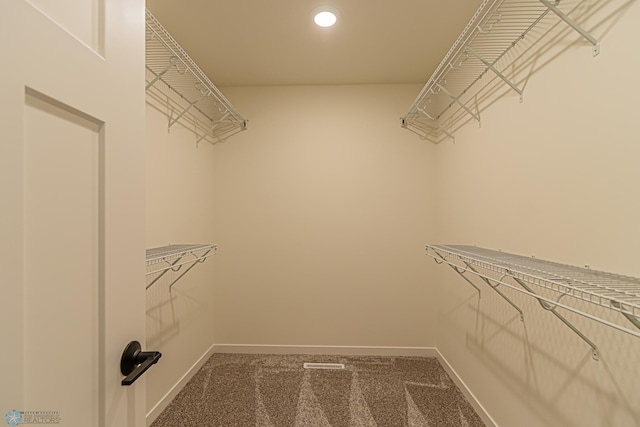 spacious closet featuring dark colored carpet