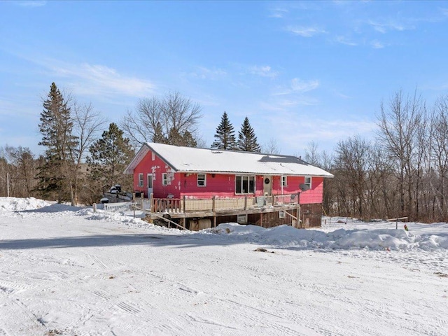 snow covered back of property with a wooden deck