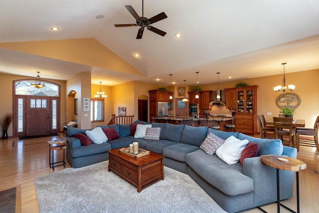 living area featuring light wood-style floors, ceiling fan with notable chandelier, high vaulted ceiling, and recessed lighting