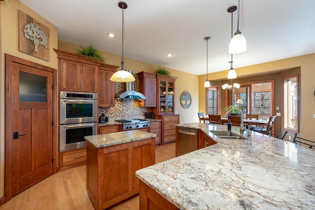 kitchen with glass insert cabinets, decorative light fixtures, stainless steel appliances, a sink, and a center island with sink