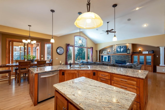 kitchen with a kitchen island with sink, open floor plan, stainless steel dishwasher, and decorative light fixtures